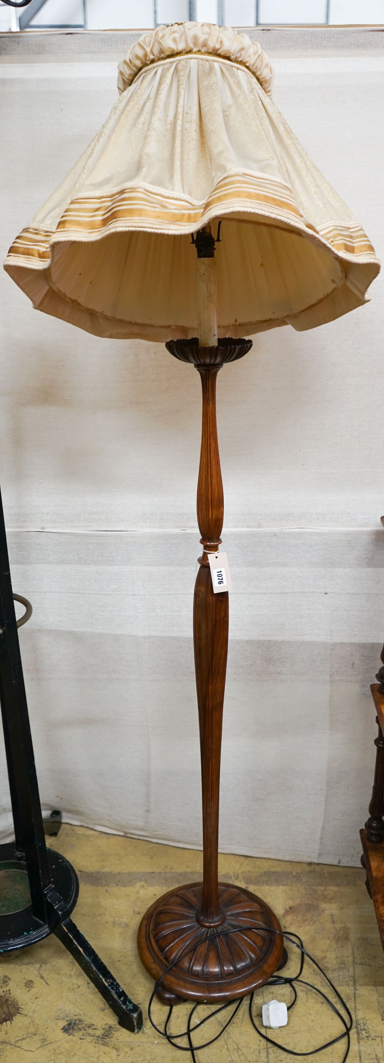 A turned and carved walnut standard lamp on circular base with bun feet, height excluding shade 132cm